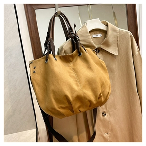Detail of mustard yellow canvas tote with metal eyelets and adjustable brown strap