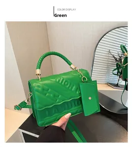 Detail of green quilted handbag featuring embossed FASHION text and woven handle