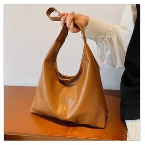 Detail of vintage brown tote bag showing pebbled leather texture and reinforced stitching