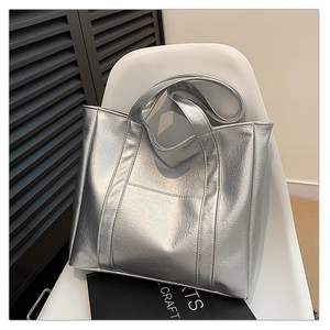 Close-up of a metallic silver tote bag with pleated texture and adjustable strap