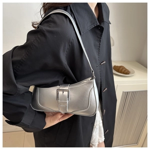 Dettaglio della borsa metallizzata argento con grande fibbia su cappotto nero