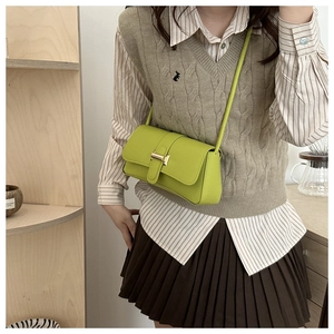 Lime green crossbody bag with gold buckle styled over a knit vest and striped shirt