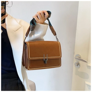 Close-up of vintage brown bag with gold studs and decorative silk scarf handle