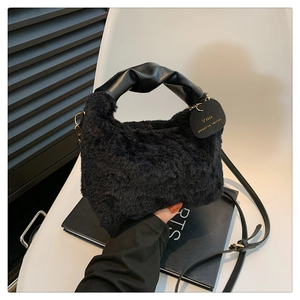 Detail of black faux fur bag with pleated leather handle and gold lettering tag