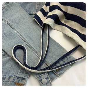 Detailed close-up of blue and white striped canvas tote bag texture on denim jacket