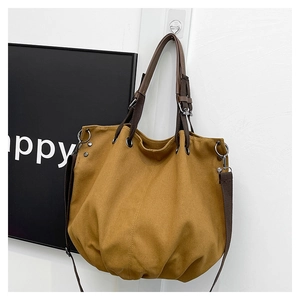 Close-up of khaki canvas tote bag with dark brown handles and silver metal rings