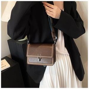 Close-up of vintage brown leather bag with stud trim and patterned woven strap