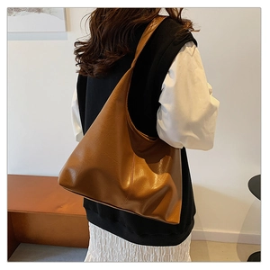 Close-up of a large brown leather hobo tote bag shown from a side-angle view on a model