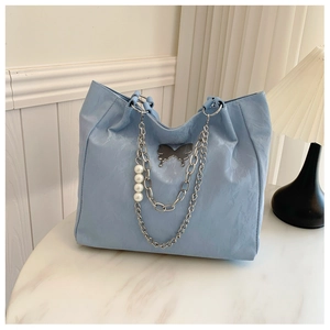 Close-up of light blue tote bag with silver butterfly clasp and pearl chain handle details