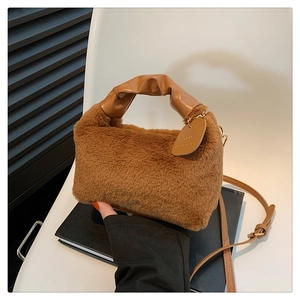 Detailed close-up of brown plush handbag with leather handle and gold metal charm