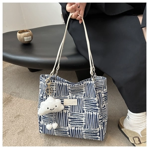 Detail of blue geometric woven tote bag with leather straps and plush cloud charm