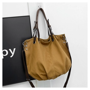 Detail of canvas tote bag showing brown leather handles and adjustable cross strap