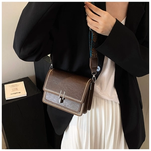 Detail of vintage brown crossbody bag featuring metal studs and a bohemian wide strap