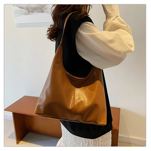 Detail of vintage brown large capacity tote bag with glossy leather texture on model