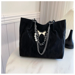 Close-up of black pleated tote bag with pearl chain strap and silver butterfly buckle