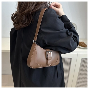Brown faux leather baguette bag with silver buckle worn on shoulder in natural light