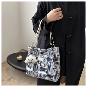 Detail of blue and white geometric canvas tote bag with a white cloud plush charm