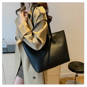 Detail of the high-quality black matte leather tote bag worn with a khaki coat