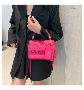 Close-up of hot pink quilted crossbody bag with FASHION embossed logo and matching charm