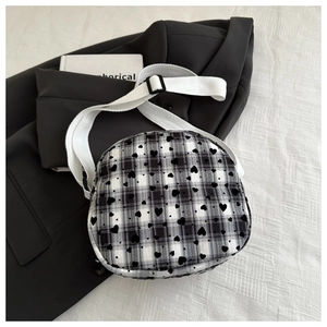 Detail of checkered crossbody bag with black heart prints and adjustable strap