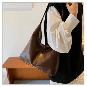 Detail of deep brown tote bag showing matte leather texture and vertical decorative stitching