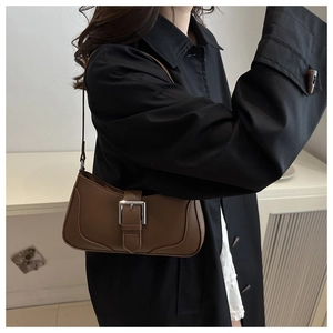 Detail of vintage brown crescent bag with a square silver metal buckle on black coat