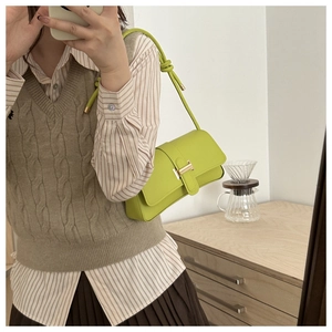 Detailed shot of lime green leather crossbody bag featuring a metal H-buckle closure