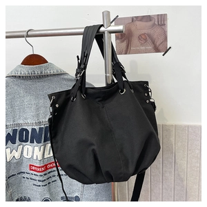 Detail of black high-density canvas tote bag with metal eyelets and wide shoulder strap