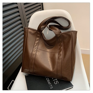 Close-up of a deep brown retro leather tote bag featuring textured finish on a white chair