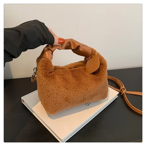 Close-up of brown plush handbag featuring ruched leather handle and metal hook detail