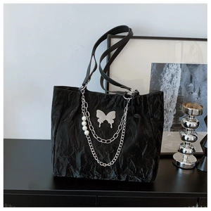 Detail of black wrinkled leather tote with silver butterfly and pearl chain ornaments