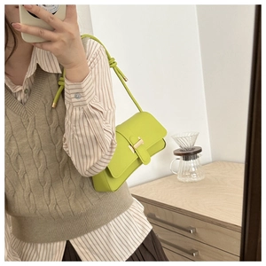 Mirror selfie showing a light green leather underarm bag with gold buckle on shoulder