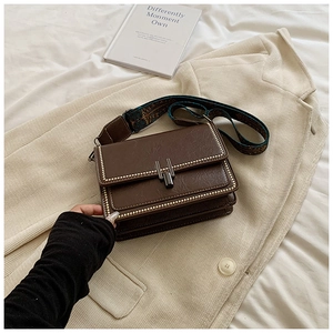 Detail of dark brown vintage crossbody bag with metal studs and ethnic pattern strap