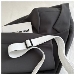 Detail of dark grey suit blazer fabric with white canvas belt and black buckle