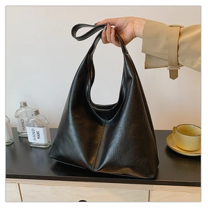 Detail of minimalist black leather tote bag with smooth texture and triangular structure