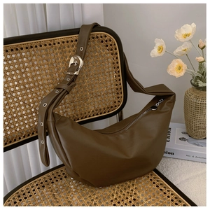 Detail of soft brown faux leather hobo bag with adjustable silver grommet strap