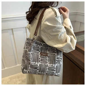 Detail of geometric pattern tote bag featuring brown leather straps and metallic rings