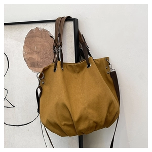 Macro detail of mustard yellow canvas tote bag featuring premium metal eyelets and texture
