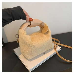 Detail of soft beige faux fur handbag featuring a knotted leather handle and gold hardware