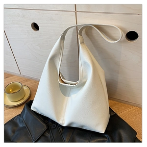 Close-up of cream textured leather hobo bag on a leather jacket with soft lighting