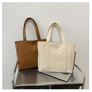 Detail of high-quality PU leather tote bags showing natural texture and front pocket