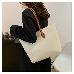 Detail view of large white tote bag with geometric stitching and brown straps on shoulder