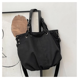 Detailed shot of black canvas tote bag with metal eyelets and adjustable strap