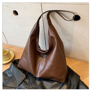 Detail of soft brown leather texture and natural folds on a large minimalist hobo tote bag