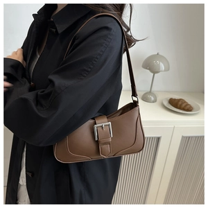 Dettaglio borsa sottobraccio in pelle marrone con cinturino vintage e fibbia in argento
