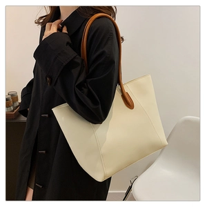Detail of minimalist cream leather tote bag with brown handles in a lifestyle setting