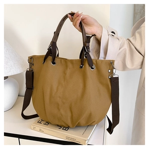 Detail of a large vintage canvas tote bag with brown leather handles and shoulder straps
