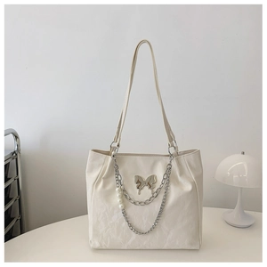 Detail of creamy white tote bag with silver butterfly pendant and pearl chain decoration