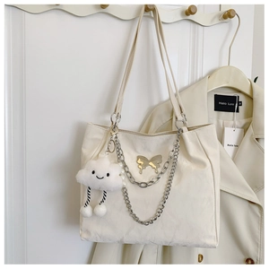 Detail of off-white tote bag featuring silver butterfly metal and double chain charms