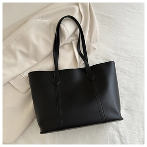 Detailansicht von oben auf eine große schwarze Leder-Tote-Bag mit Ziernähten und glatter Textur